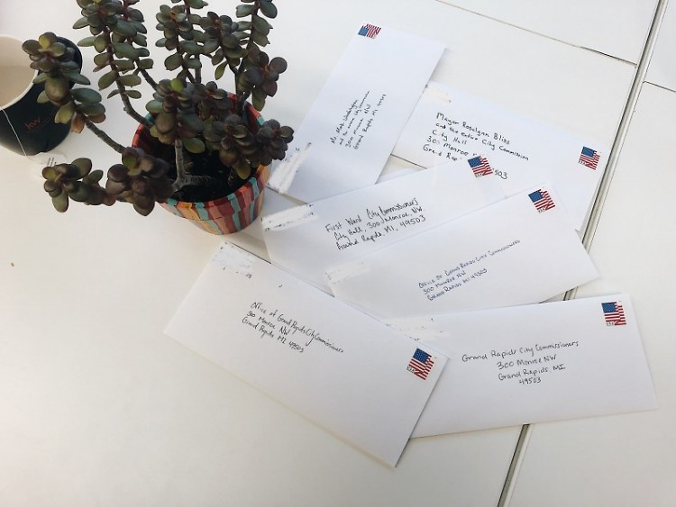 Resident-written letters, addressed to City Commission, adorn a Dwelling Place table after a letter-writing workshop.
