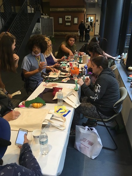 Residents gather around a community table to make fall-themed artwork