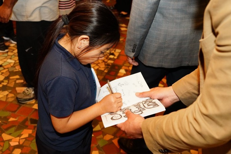 A young author signs a book during the Bloom Cherry Bloom Tree celebration