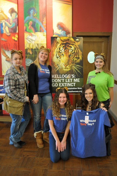 A group of volunteers and participants gather around a sign pleading Kellogg's to help save the Sumatran Tiger. 