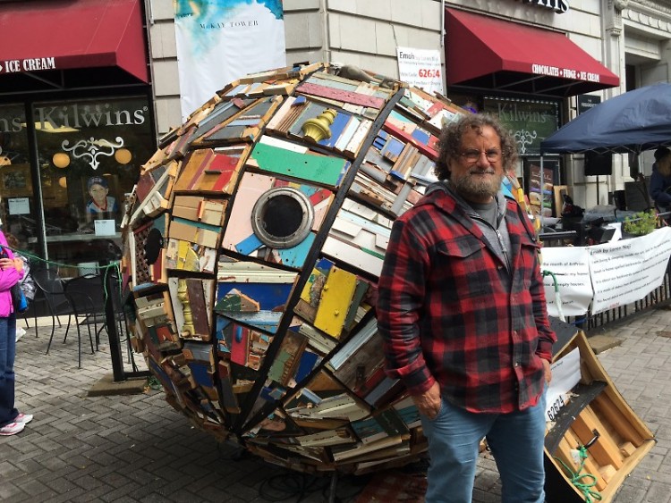 Artist Loren Naji stands outside of his sculpture "Emoh," which represents society's "backwards" approach to homelessness.