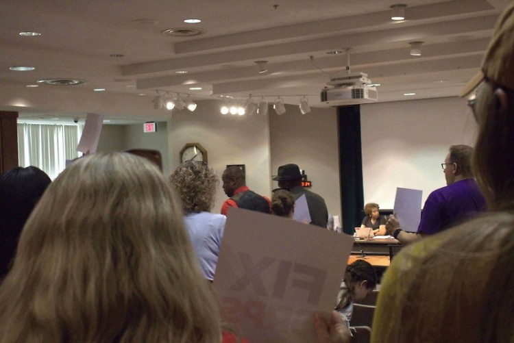 Parents and community members hold "FIX GRPS" signs during July 22, 2024 Grand Rapids Public Schools board meeting.