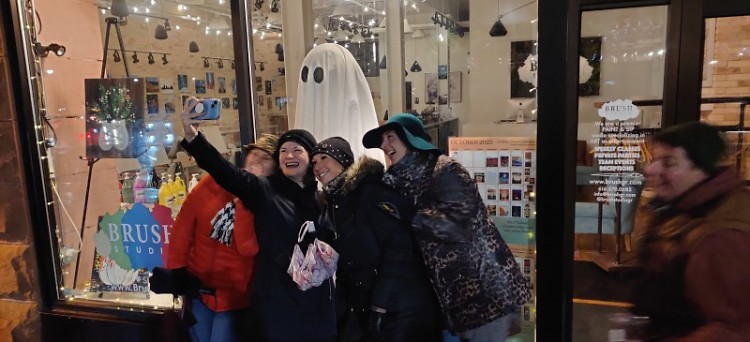 A group of tour attendees pose with a ghost decoration downtown Grand Rapids.