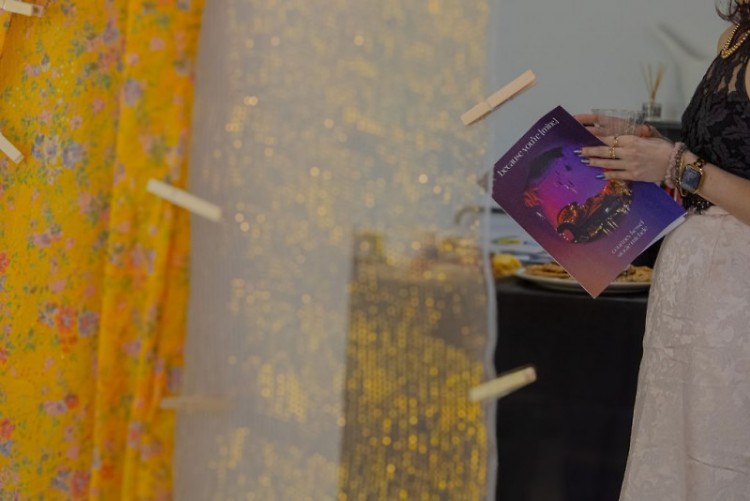 A visitor holds a colorful exhibition booklet titled "because you're [mine]"