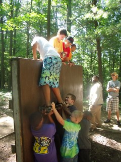 A cabin of campers taking on The Wall Challenge at Camp Tall Turf 