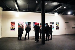 Visitors look at the artwork on display in the black and white Con Artist Crew gallery 