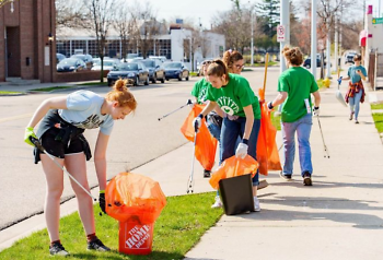 Volunteers use bright-colored bags while removing litter and unwanted vegetation from the neighborhood streetscape