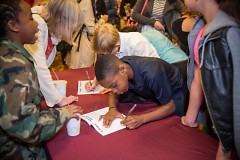 Students sign their work at the Wealthy Theatre