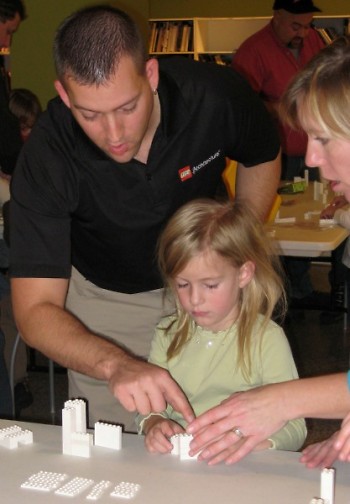 Adam Reed Tucker works with a child at a seminar to show the many uses of the LEGO brick.