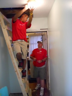 Two Lowe's employees work to put in a new, energy efficient lightbulb, using the new step ladder.