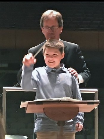 Emmet Claypool, age 10, conducts the Grand Rapids Symphony, assisted by John Varineau.
