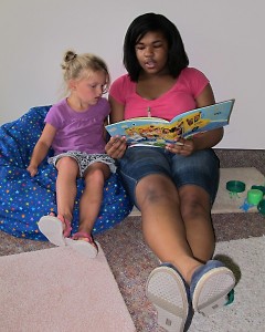A teen volunteer reads with a child