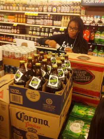 A volunteer works diligently to place stickers on alcoholic beverages