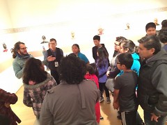Students and families gather around Salvador Jimenez Flores as he talks about his Artprize entry at the GRAM