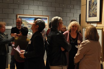 Artists and community members mingle together admiring the exhibits.