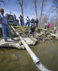 Here, year-old Steelhead Salmon are being stocked in the Huron River at Rockwood.